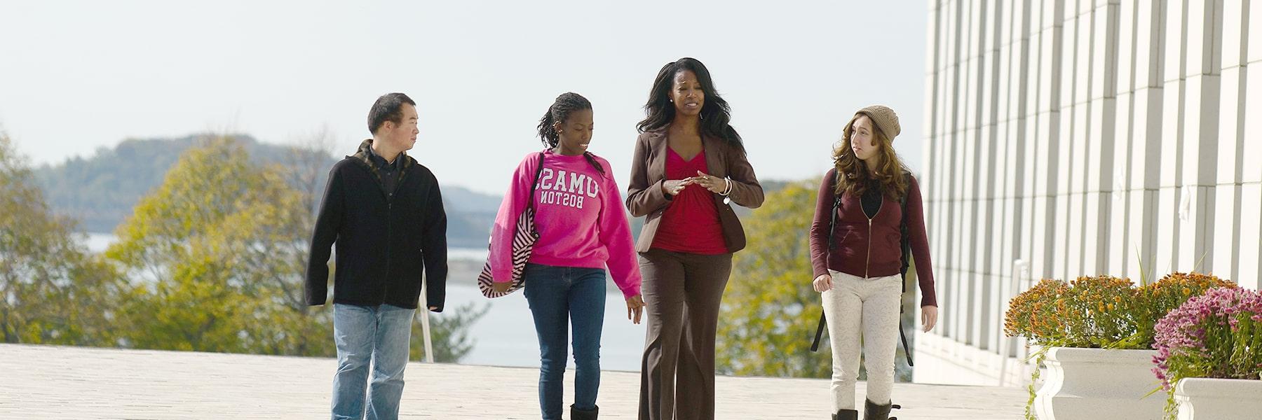 Students walk with a financial aid counselor on the plaza.