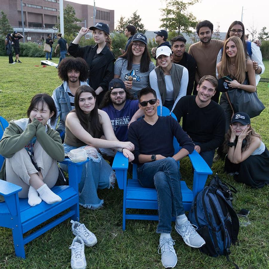 一群学生在校园中心草坪上的蓝色椅子上摆好姿势.