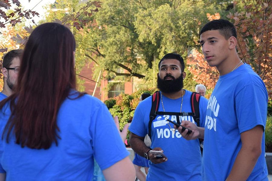 Students in UMass Boston t-shirts talking on move-in day by residence halls.